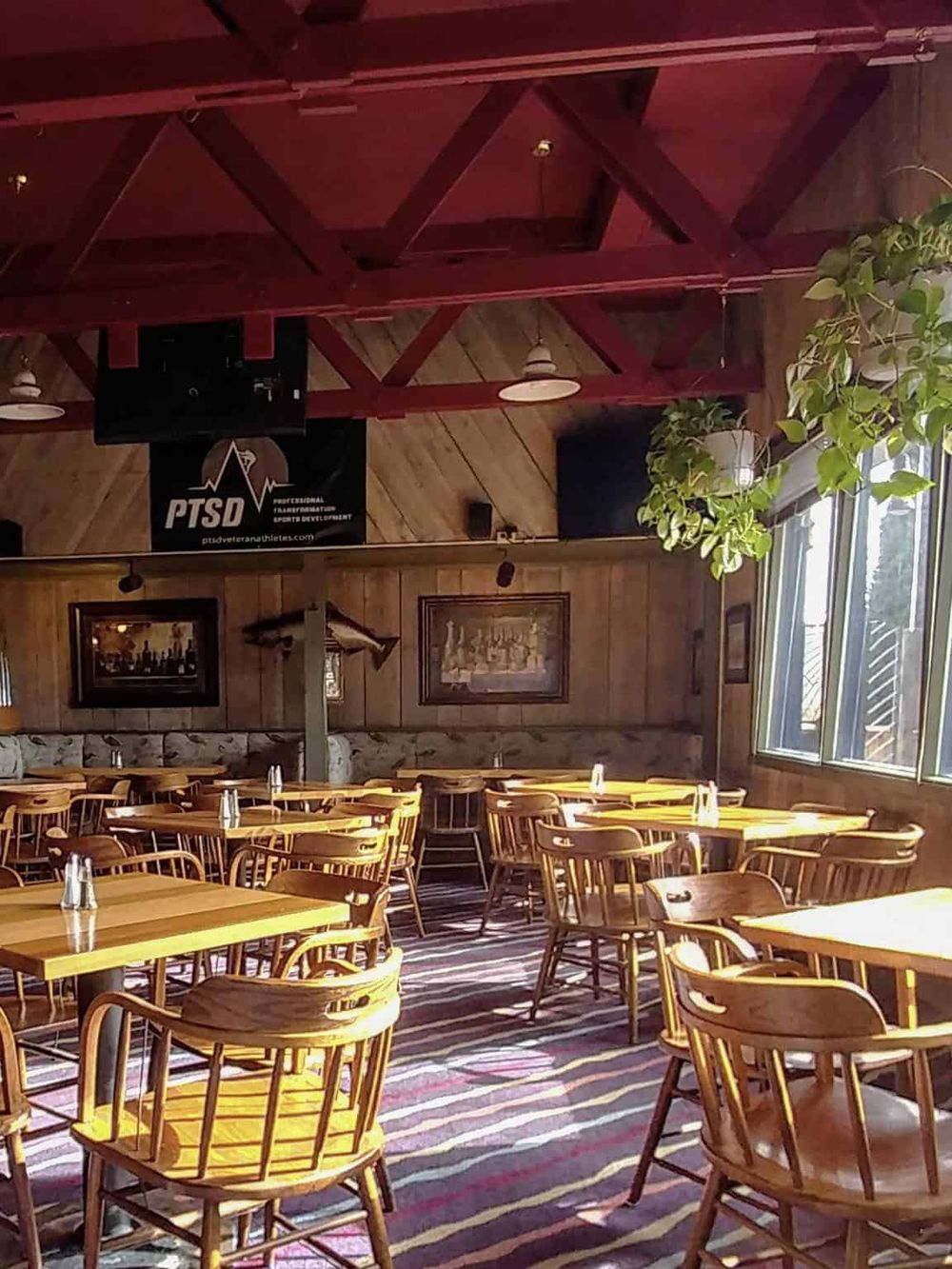 Cozy restaurant interior with wooden tables and chairs, natural light, and wall decor, ideal for dining and socializing.