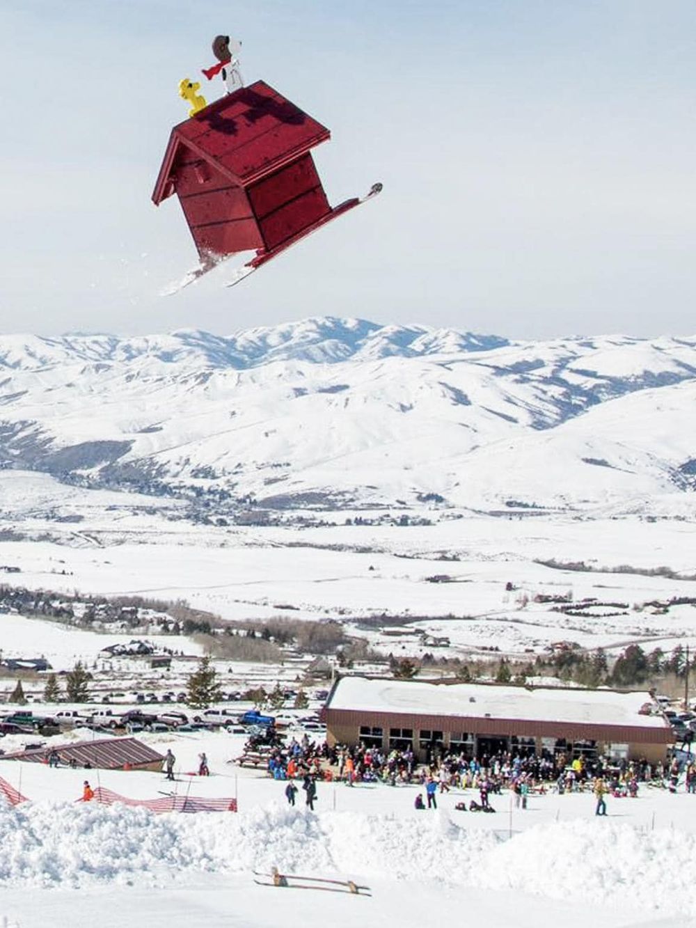 A whimsical red house flying over snowy mountain landscape with people enjoying winter sports at a ski resort.