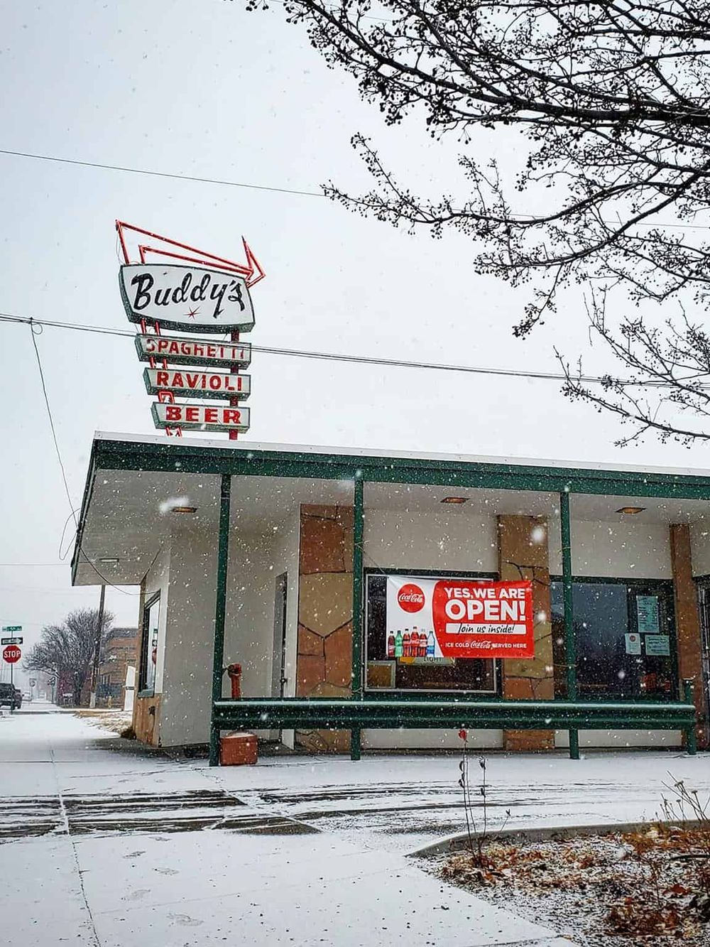 Cozy restaurant with neon sign, snow-covered sidewalk, inviting atmosphere, perfect for dining near QuestForDirections.