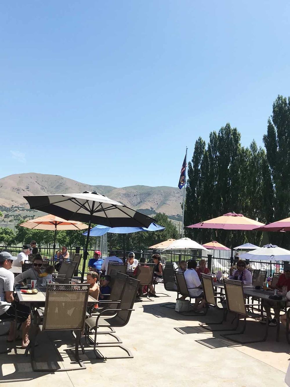Relaxing outdoor dining area with scenic mountain views and colorful umbrellas, ideal for family gatherings and summer meals.