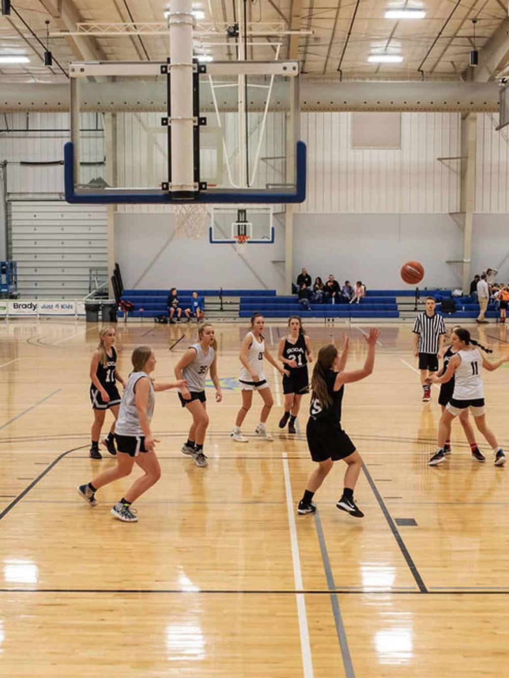Kids playing basketball in indoor gymnasium for youth sports activity.