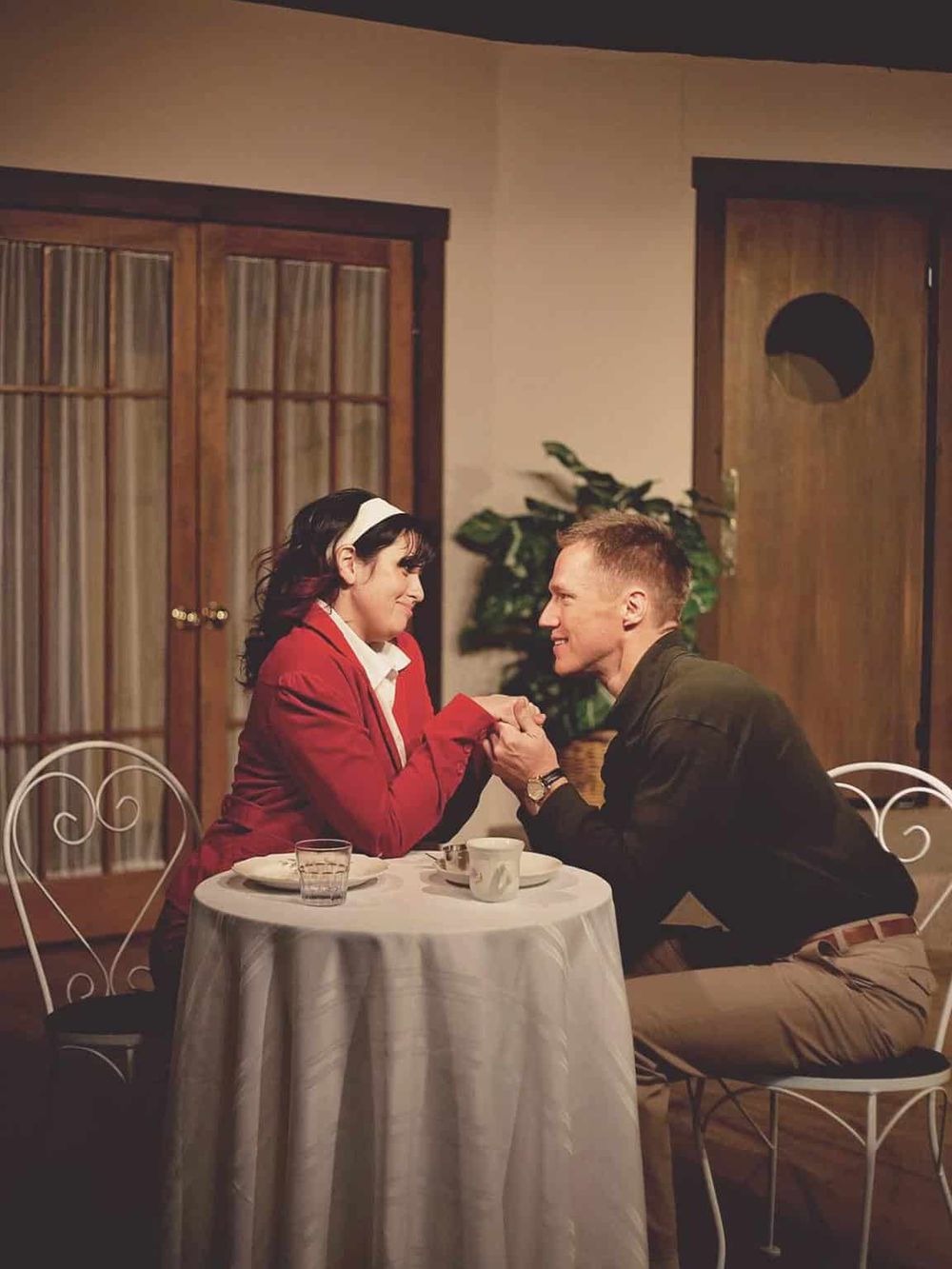 Romantic couple having dinner, holding hands at a cozy restaurant table, sharing an intimate moment.