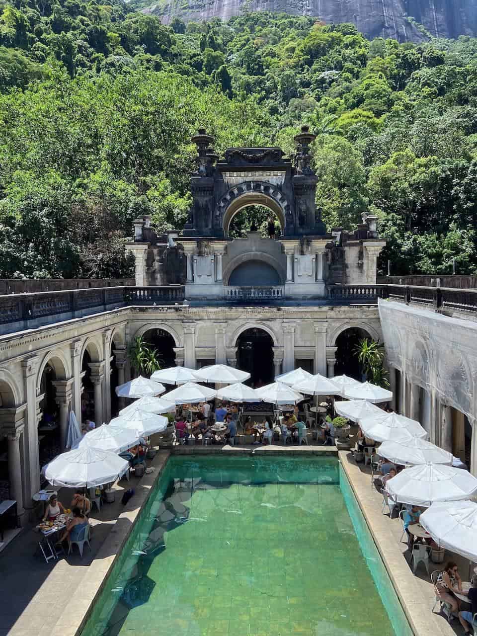 Historic outdoor pool and terrace at Quest for Directions, surrounded by lush mountains and greenery.