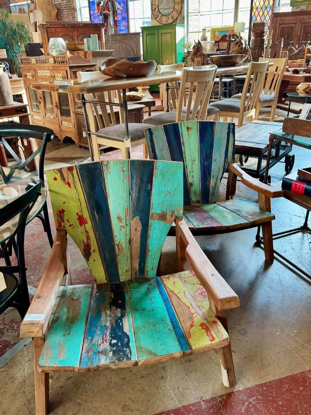 Colorful reclaimed wood chairs in a vintage furniture store display.