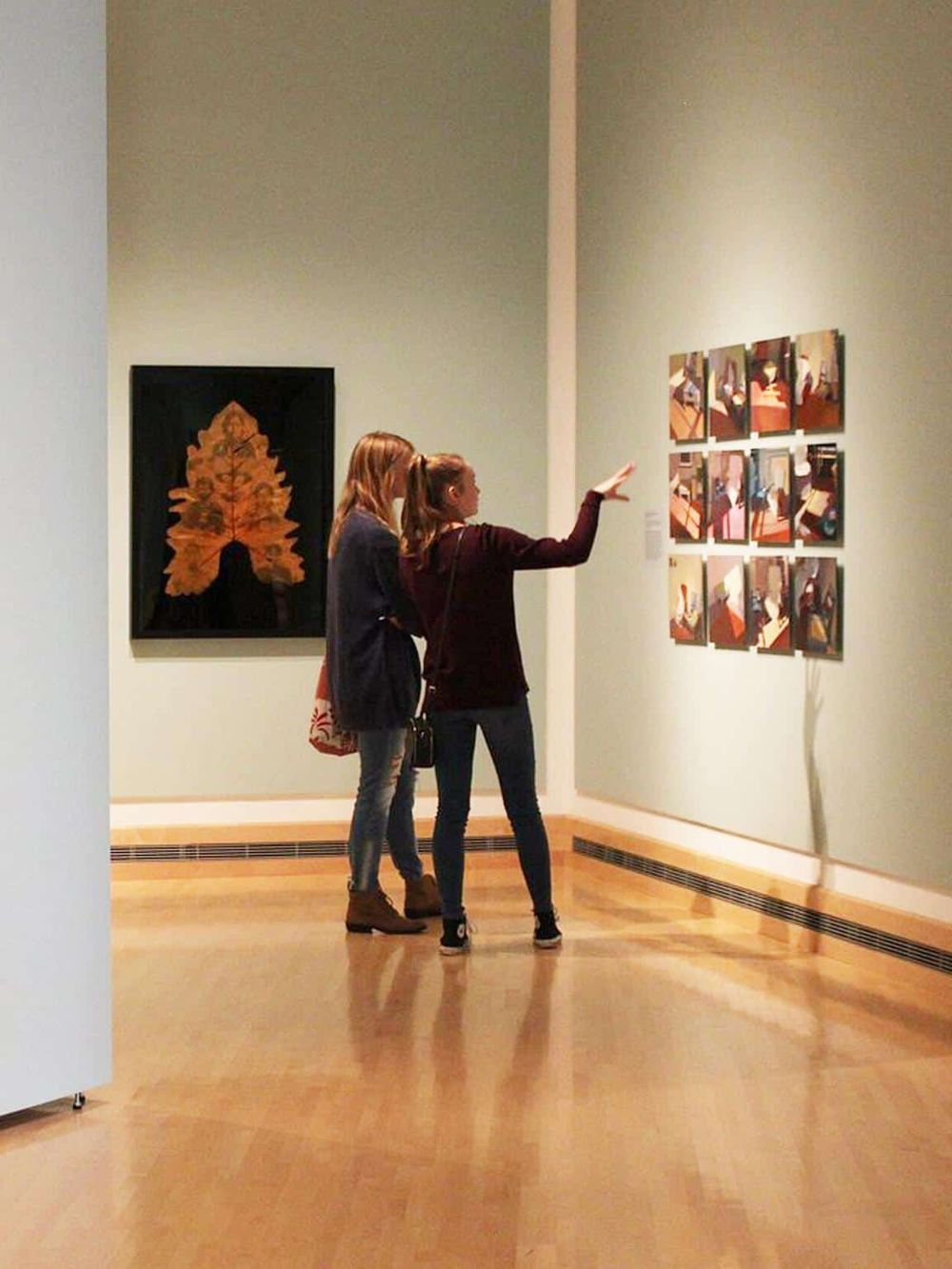 Colorful artwork at an art gallery, visitors admiring paintings on display, showcasing cultural exploration and art appreciation.