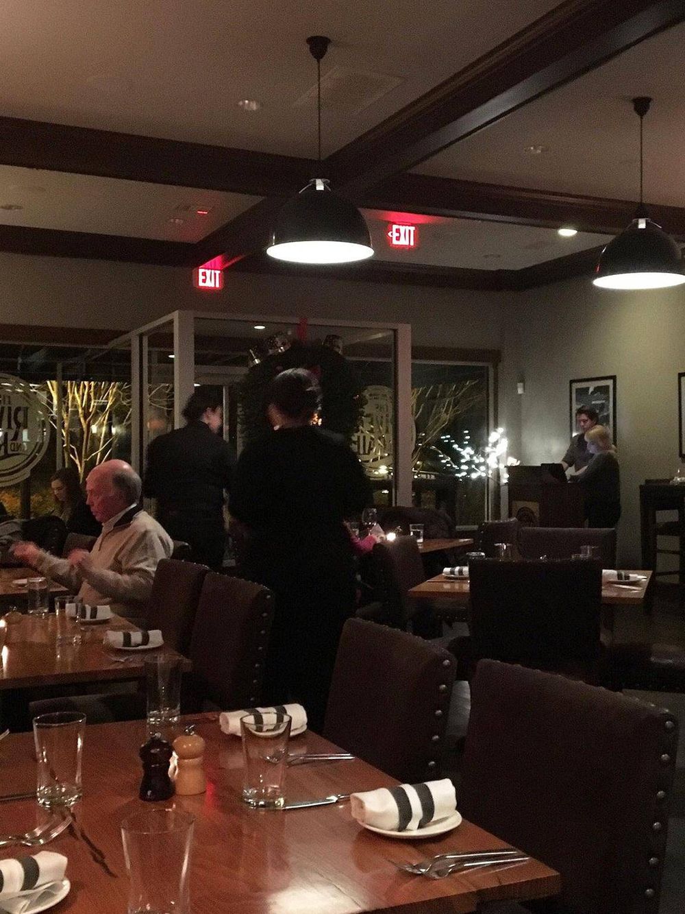 Warm inviting restaurant interior with dining tables, ambient lighting, and waitstaff providing excellent service.