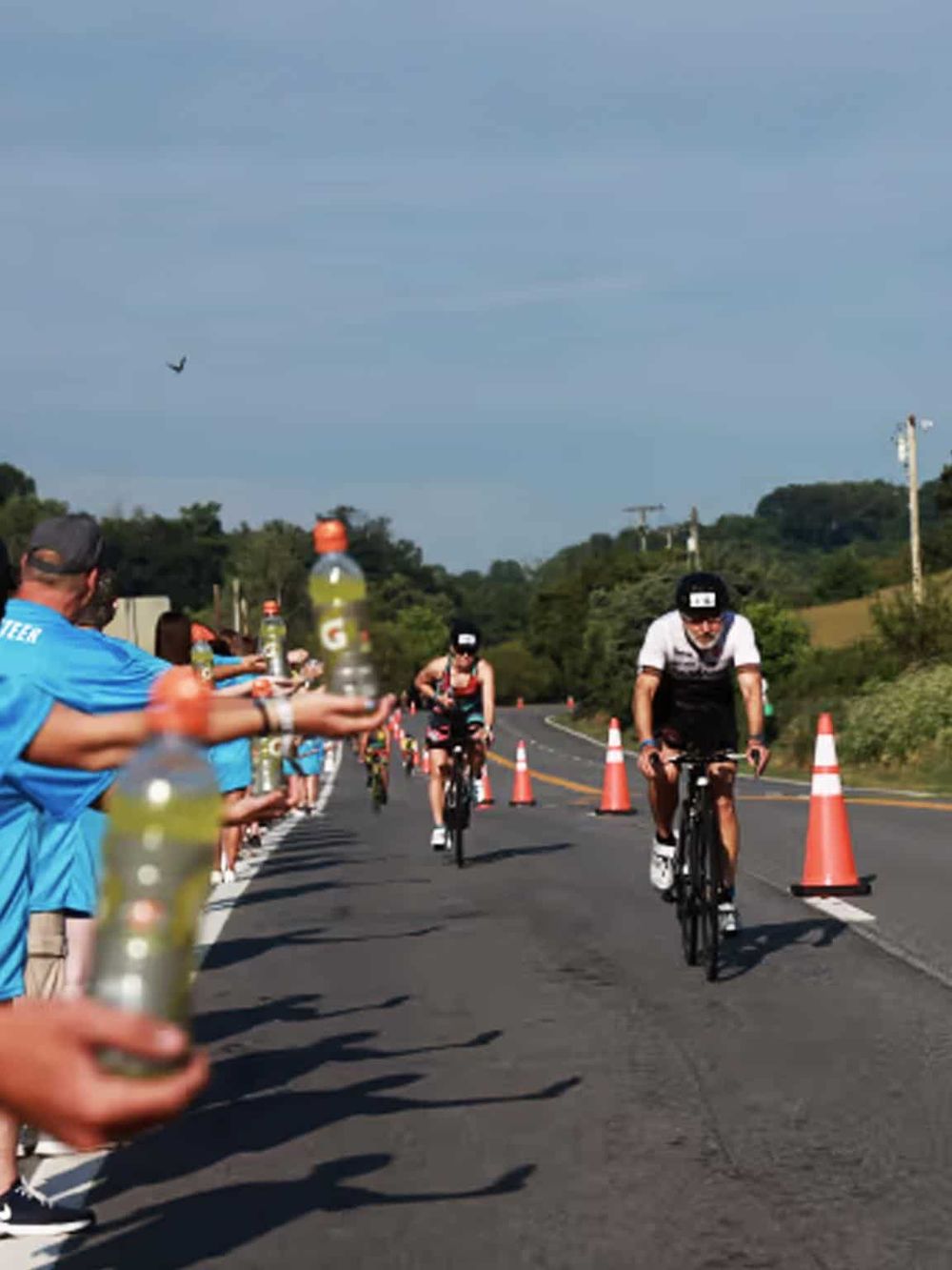 Cyclists participating in a road race with spectators supporting along the roadside.