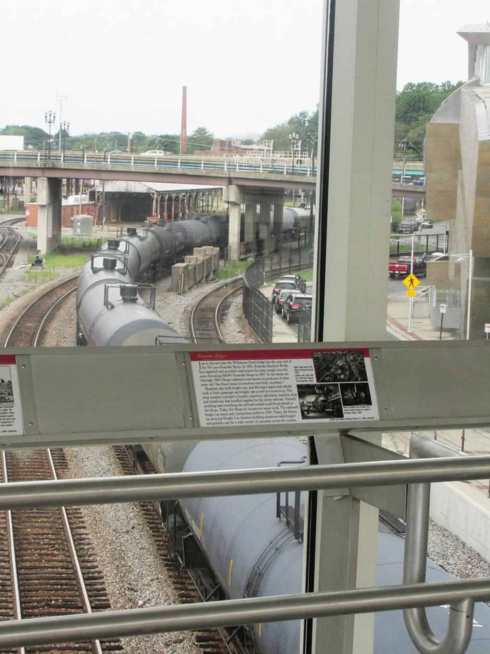 Historic railroad train scene with moving freight trains viewed from an elevated station platform.