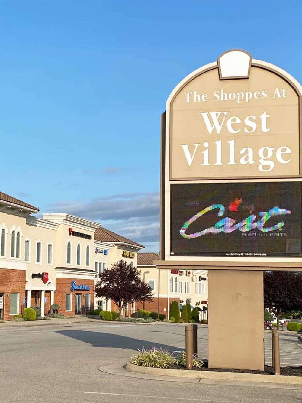 Vibrant shopping plaza signage at West Village, digital retail and outlet stores, inviting outdoor shopping experience.