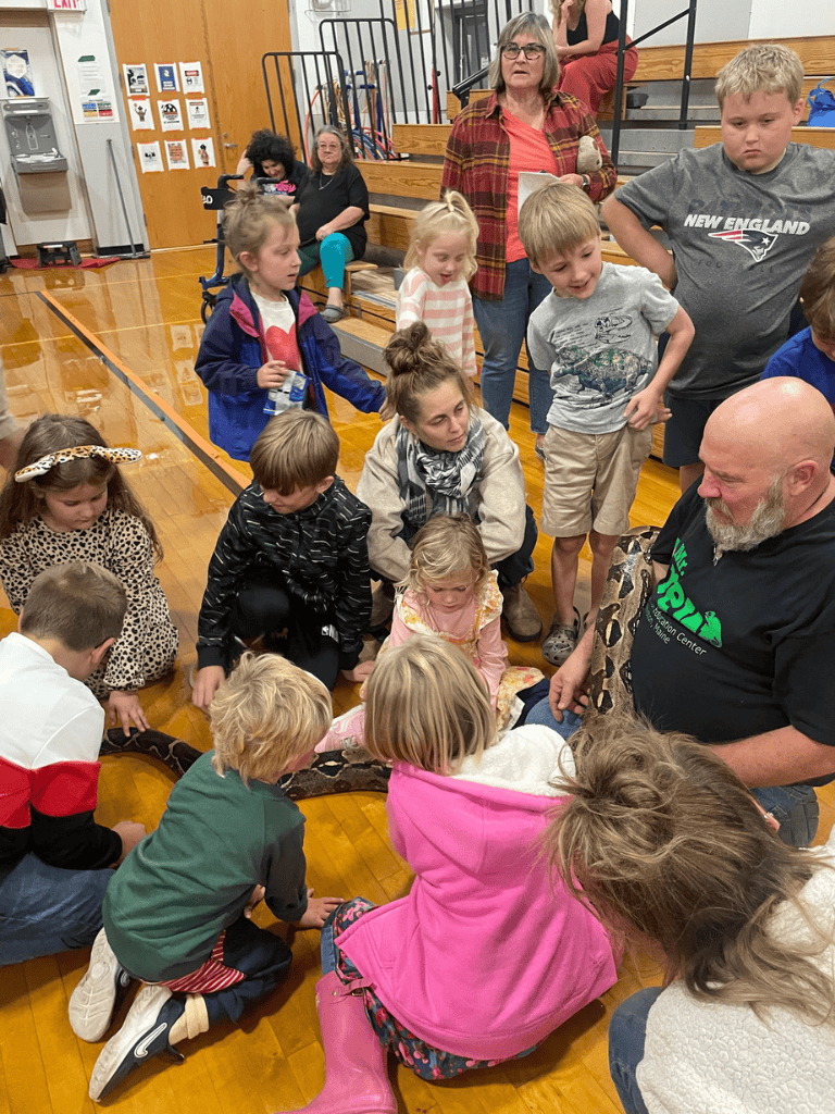Aussie-friendly education event with children and adults engaging with a snake demonstration.