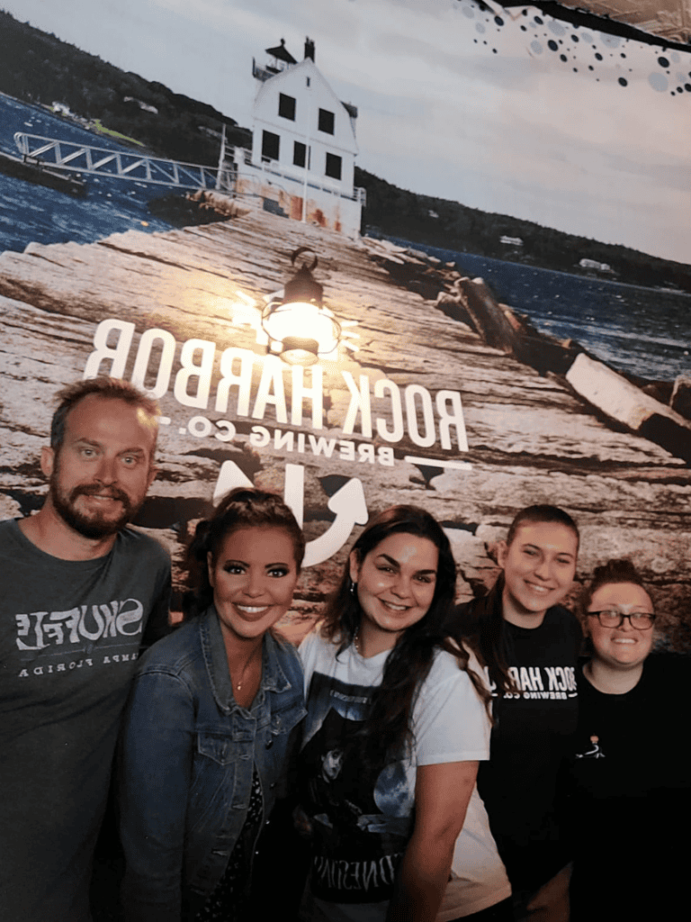 Bright group of friends at Rock Harbor Brewing Co, enjoying a casual outing by the waterfront.