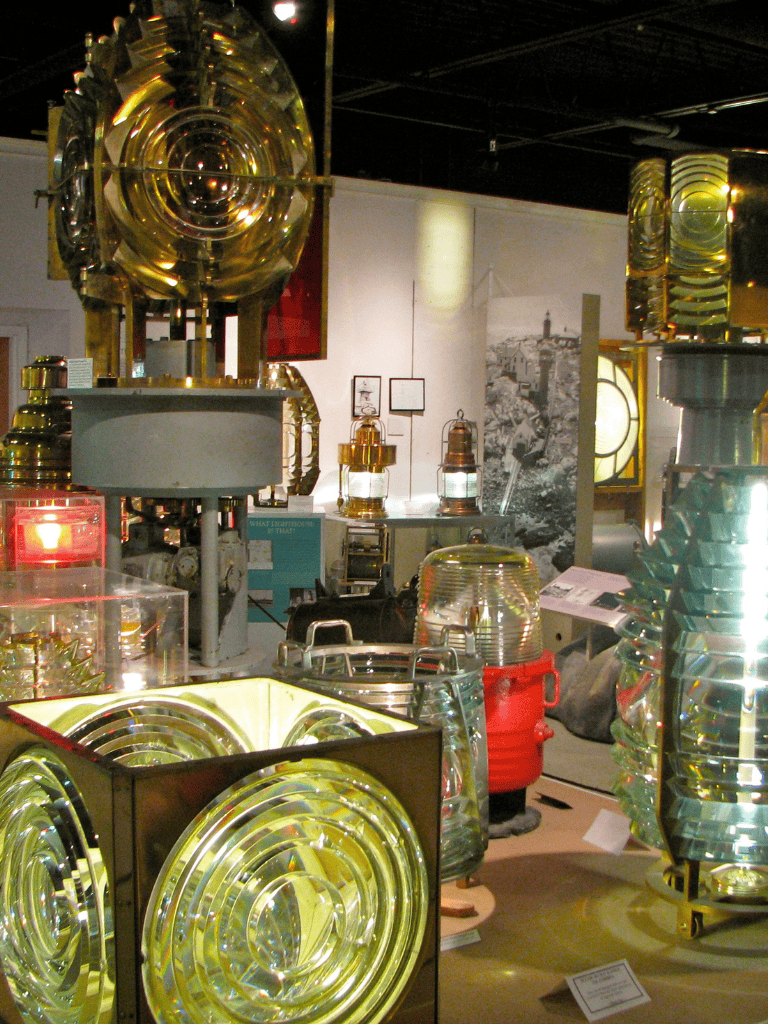 Reflective lighthouse lens displays at a museum exhibit.