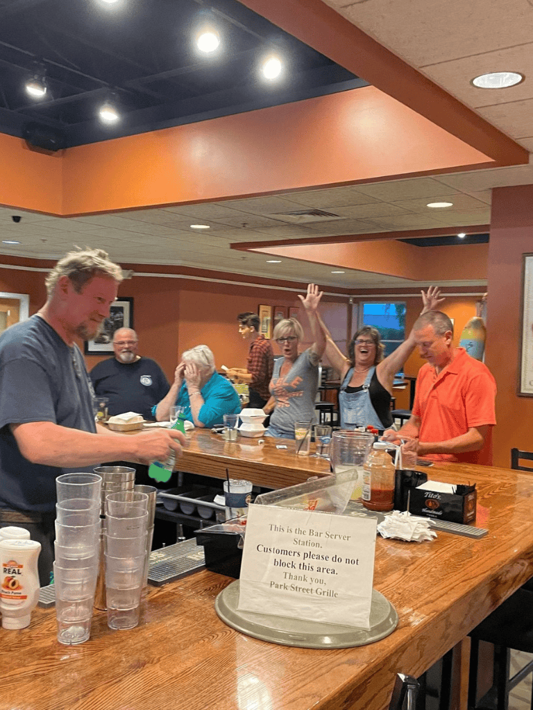 Cheerful group celebrating at bar with drinks and casual dining.