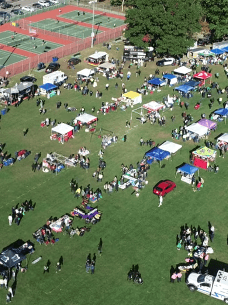 Colorful outdoor community event with tents and sports courts, promoting local engagement and recreation.