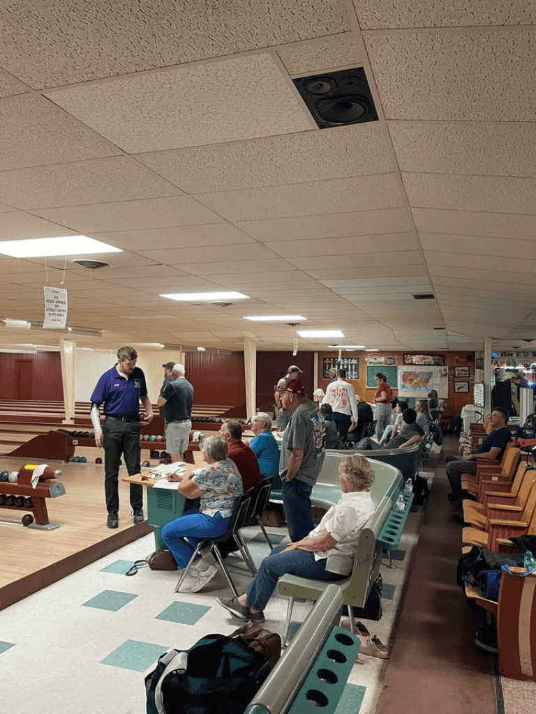 Busy bowling alley with players, spectators, and staff enjoying a game night.