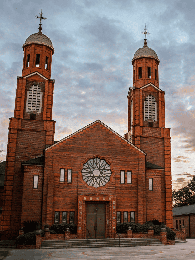 Cathedral with twin bell towers and rose window, red brick exterior, religious architecture.