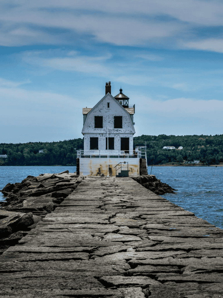 Seaside lighthouse on rocky pier, scenic coastal destination for maritime navigation and exploration.