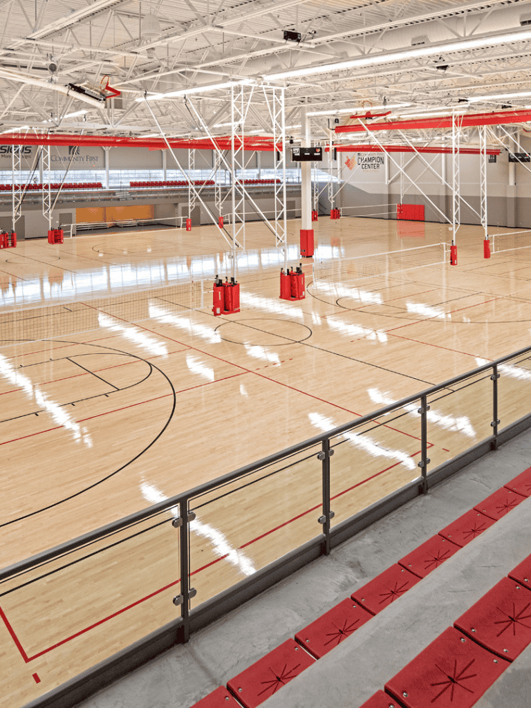 Climatized indoor basketball court with polished wood floor and red seating at QuestForDirections.