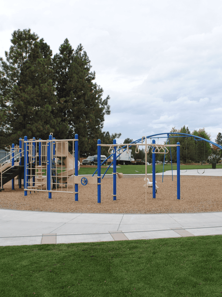 Colorful playground equipment for children at QuestForDirections park, featuring swings, slides, and climbing structures.