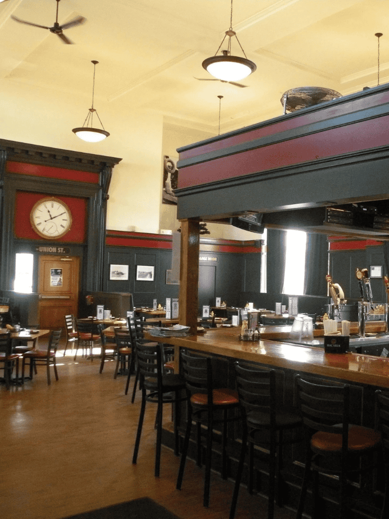 A cozy pub interior with vintage decor, high tables, and bar seating, perfect for dining and drinks.