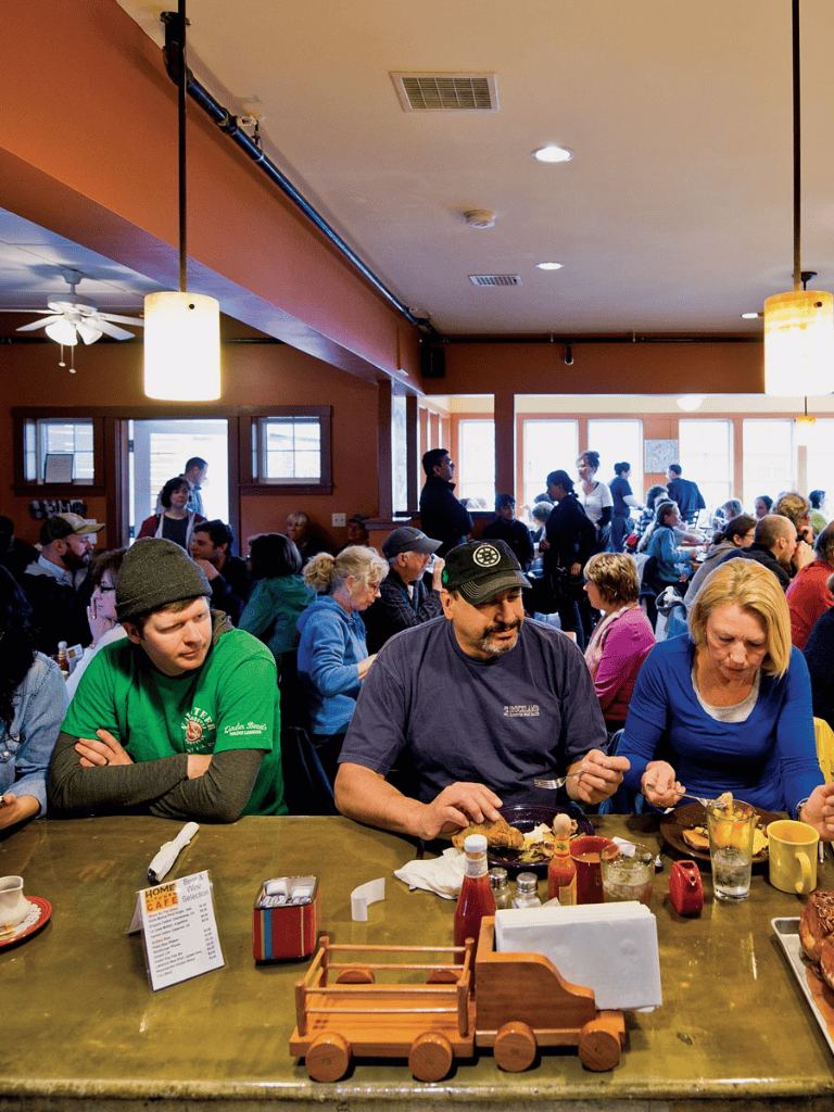 Enjoying breakfast at a busy restaurant with diverse group of people and cozy atmosphere.