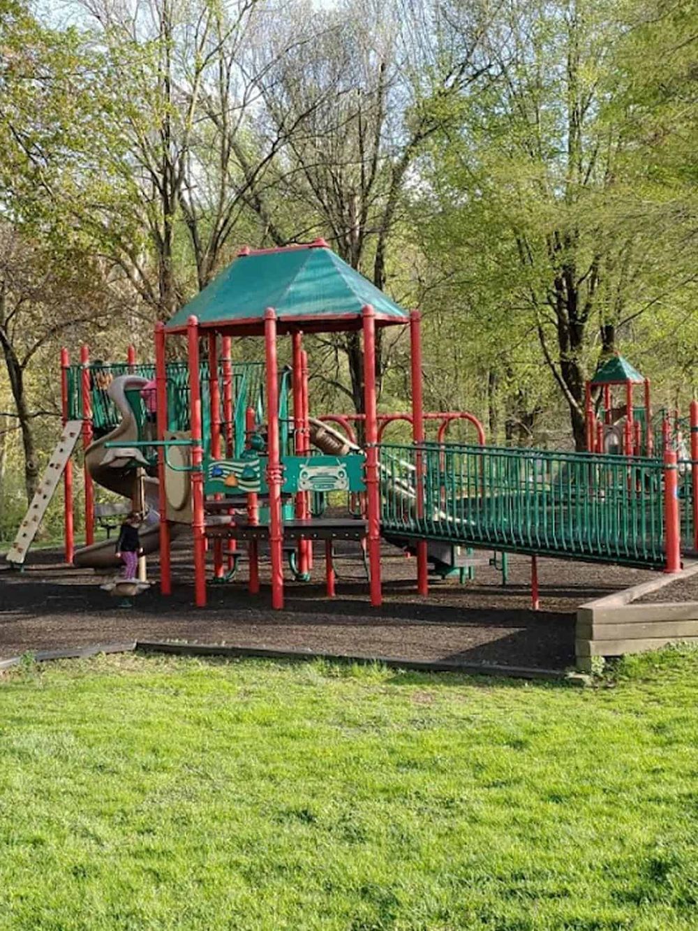 Colorful playground equipment in a park surrounded by trees and greenery.