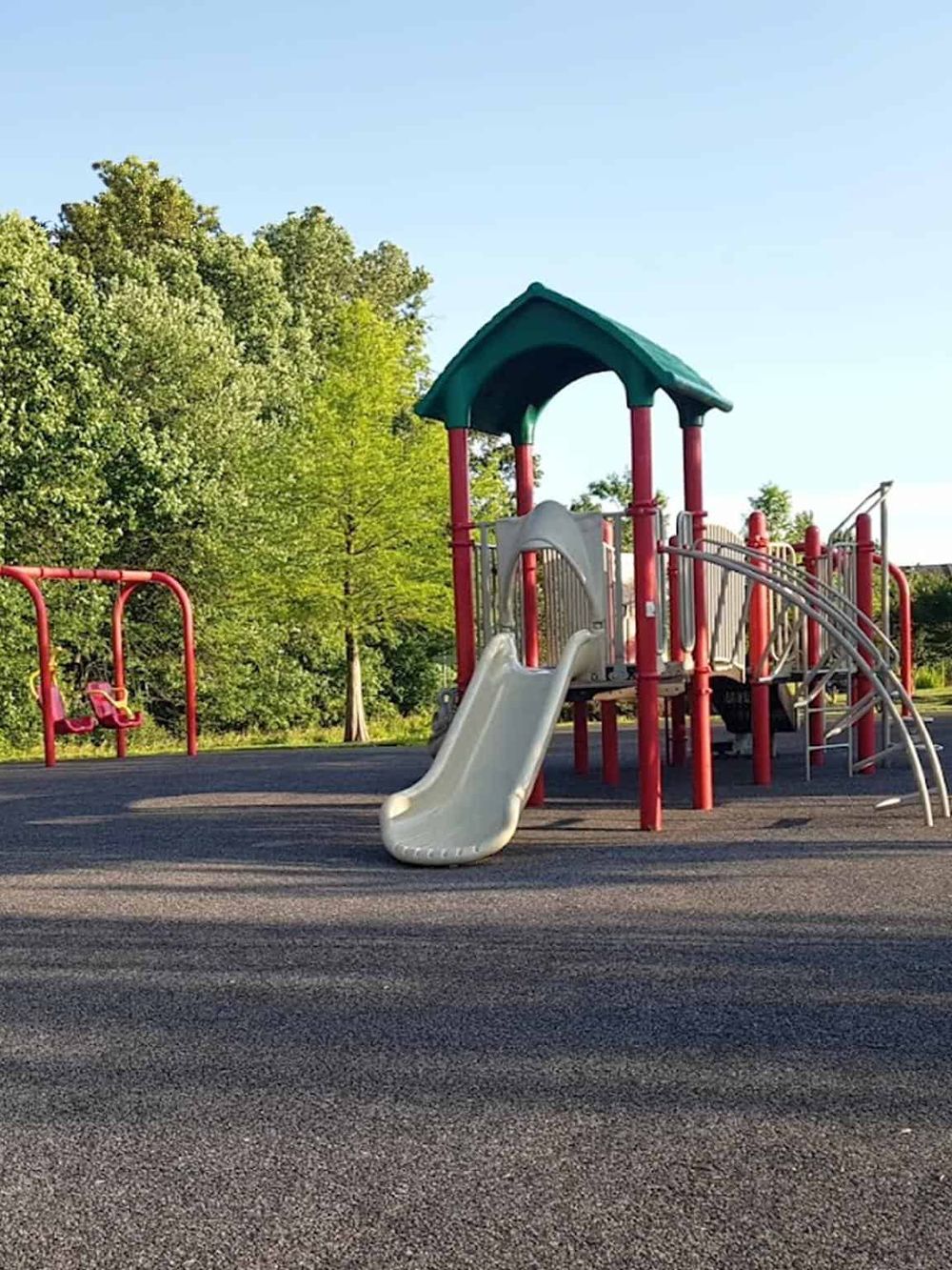 Colorful children's playground with slides, swings, and climbing structures in a park setting.
