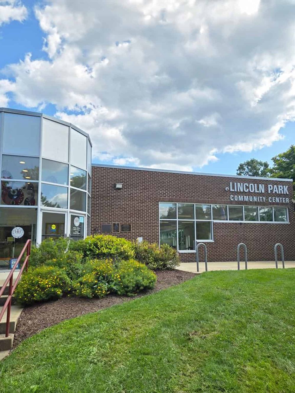 Bright Lincoln Park Community Center with green landscaping and cloudy sky.