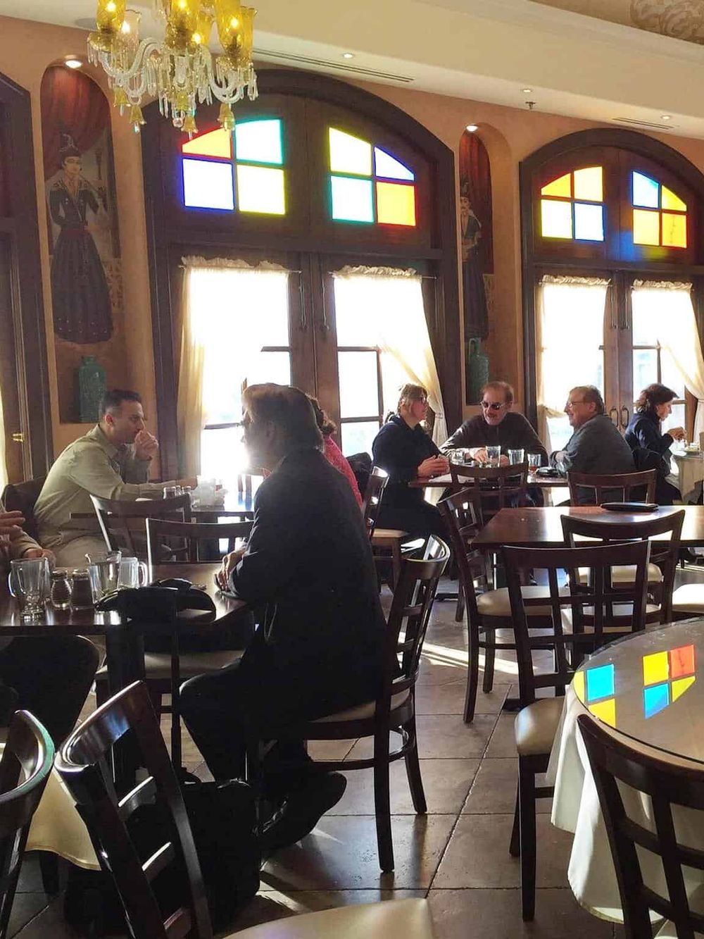 Brightly lit restaurant interior with stained glass windows and elegant chandeliers.