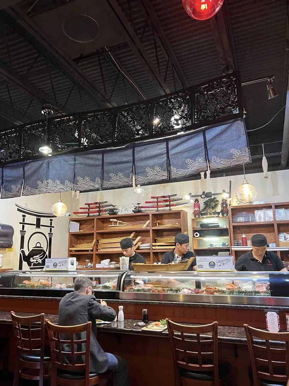 Traditional Japanese sushi restaurant interior with sushi chefs preparing dishes.