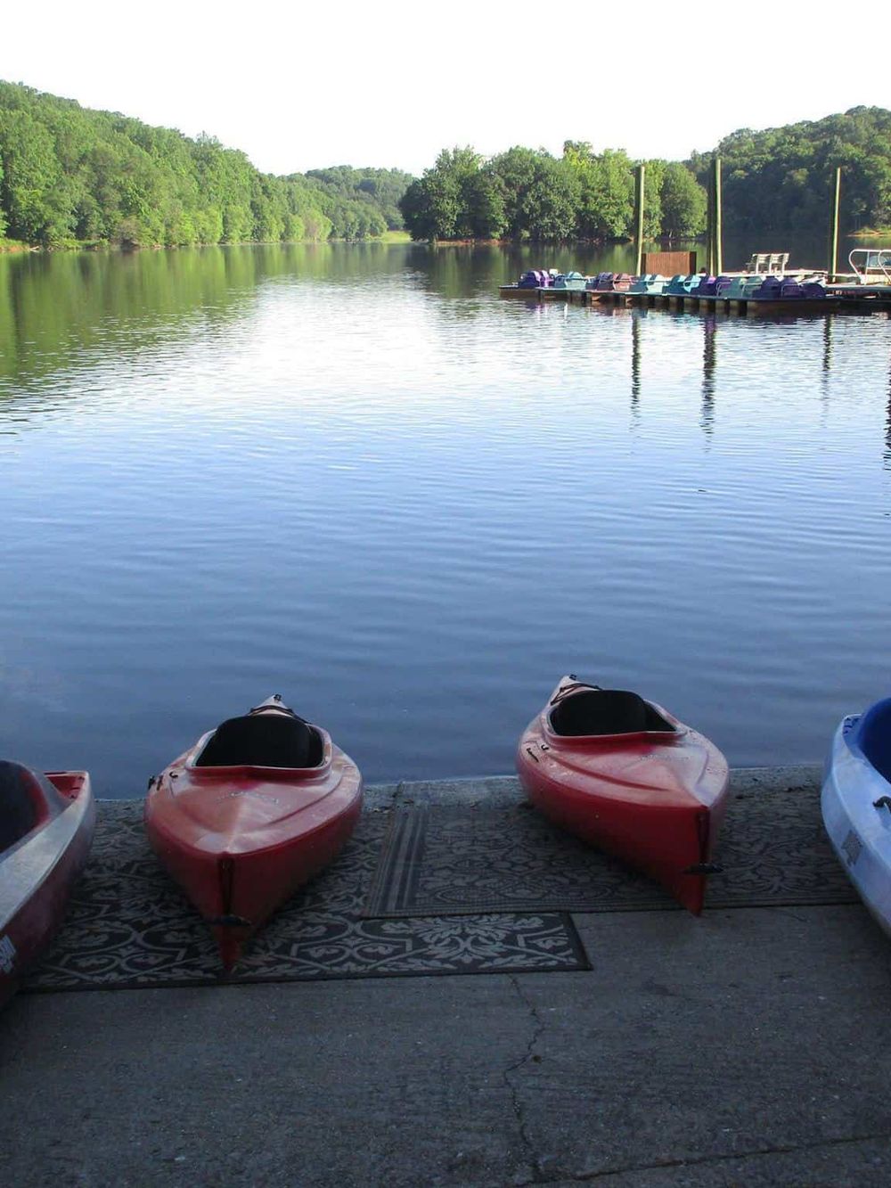 Calm lake with kayaks on shore, scenic nature, outdoor adventure, water activity, peaceful boating | QuestForDirections.