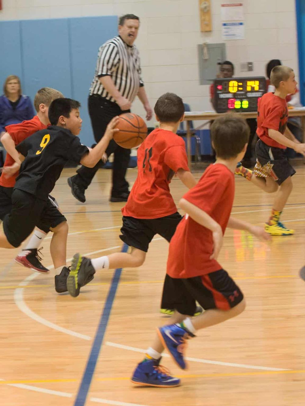 Basketball game with kids playing and a referee in action.
