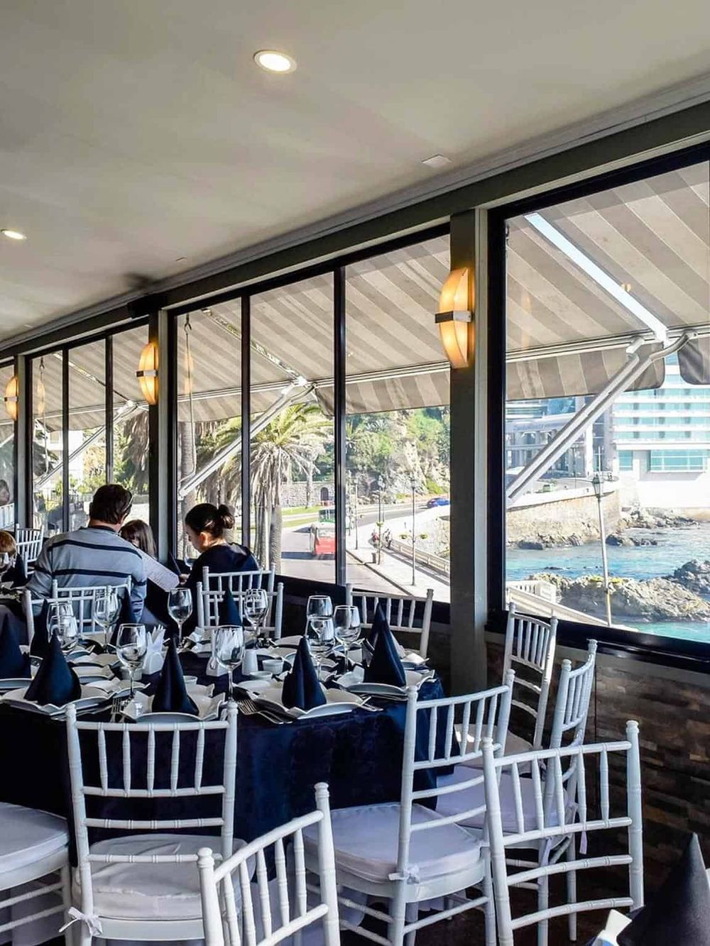 Bright waterfront restaurant dining with elegant table settings and ocean views.