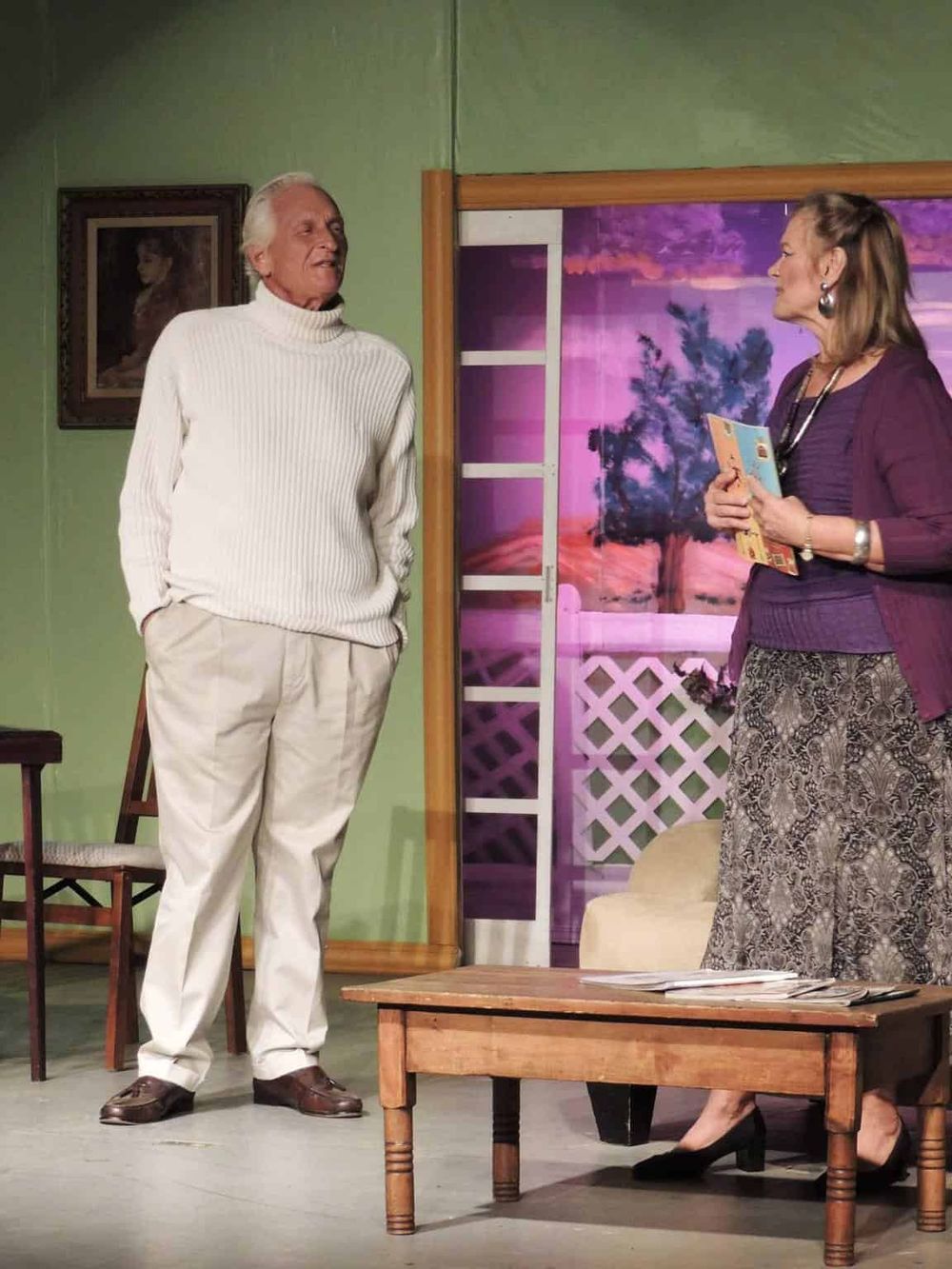 Older man and woman in conversation on stage, part of theatrical production at QuestForDirections.