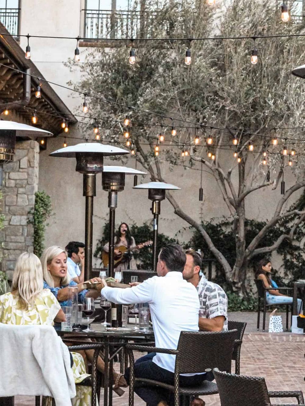 Outdoor dining with string lights and heaters, live music performance, patio setting for a memorable dinner experience, QuestForDirections.