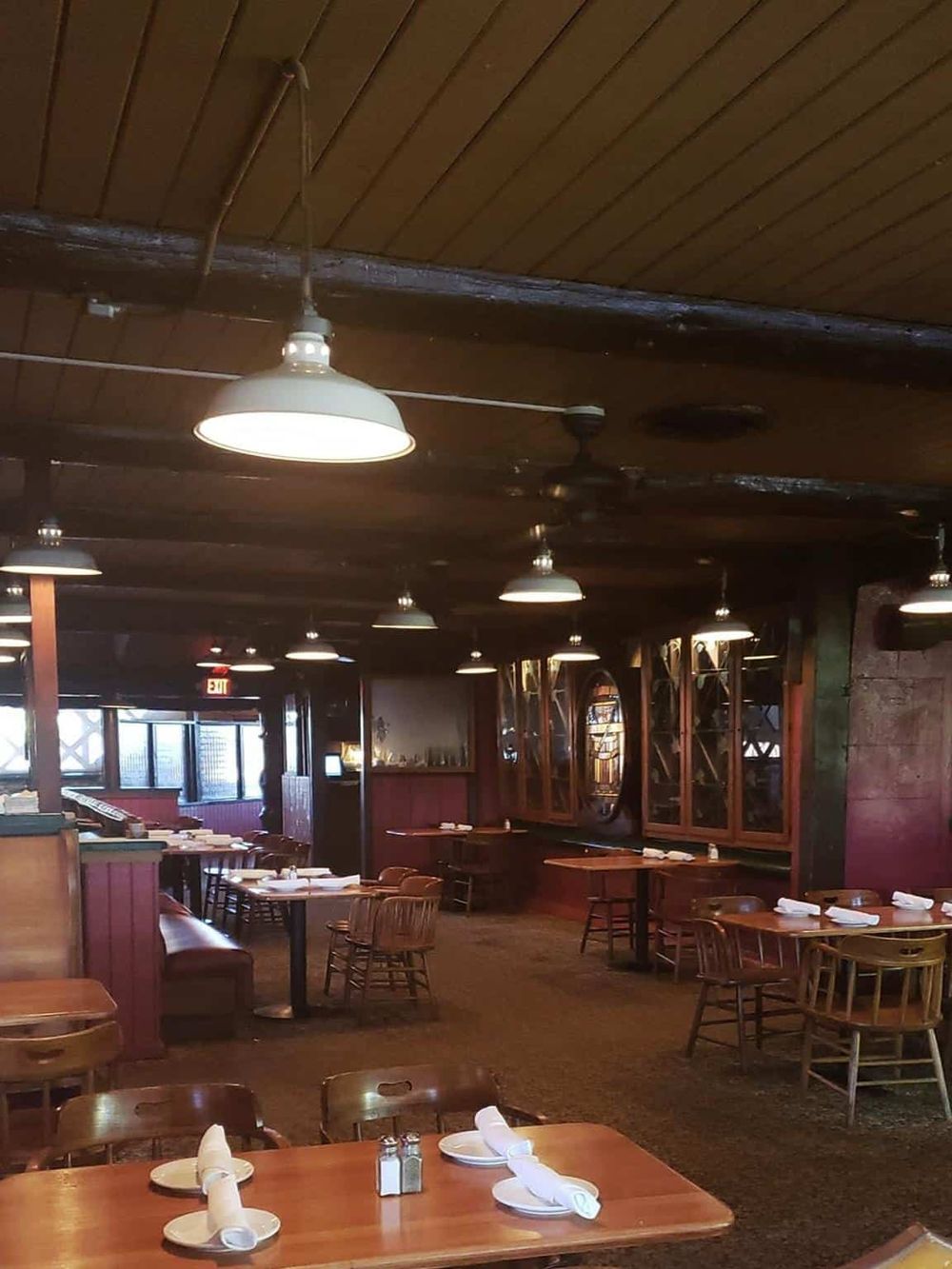 Cozy restaurant interior with wooden accents, warm lighting, and neatly arranged tables for dining.