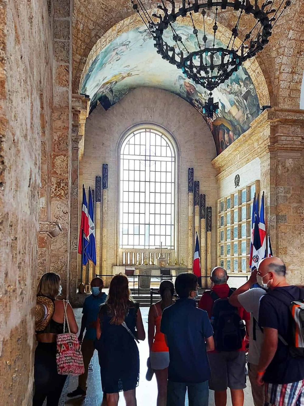 Ancient church interior with visitors observing historical artifacts and flags, showcasing the historic architecture and cultural heritage.