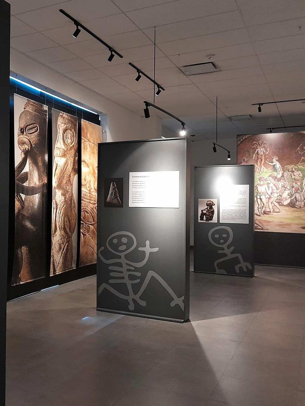 Ancient artifact exhibit with educational display panels and prehistoric art images in museum setting.