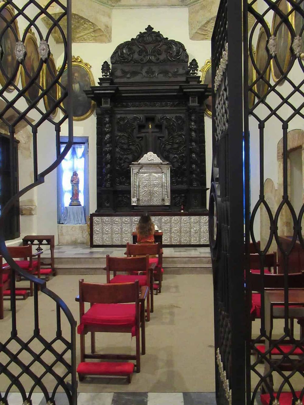 Ancient church interior with altar, religious statues, and ornate black woodwork, showcasing sacred space and Christian worship.
