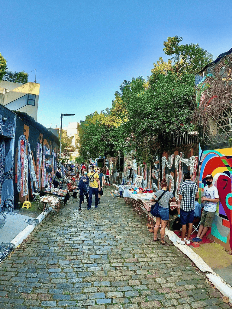 Colorful street market with vibrant murals and art vendors in Mexico City.