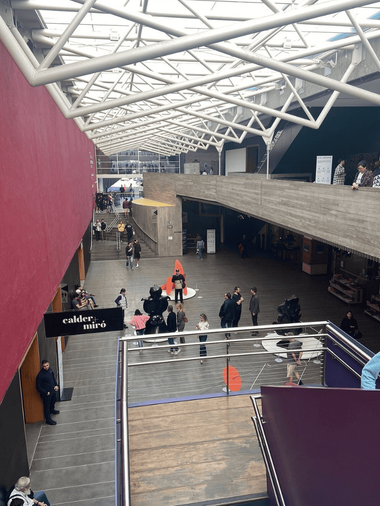 Modern indoor public space at QuestForDirections, vibrant architecture, visitors exploring, art installations, and shopping area.