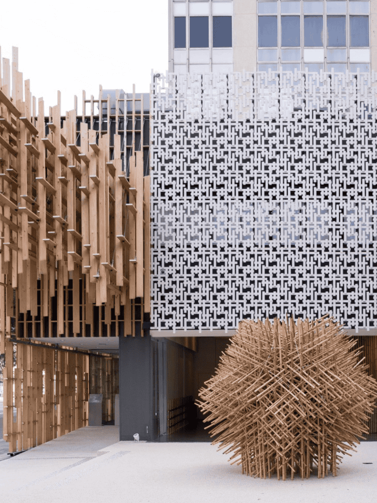 Wooden architectural facade with intricate geometric design and art installation, modern building exterior.