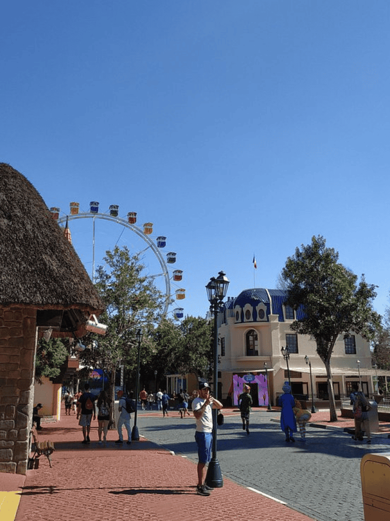 Bright day at QuestForDirections theme park with Ferris wheel and lively visitors.
