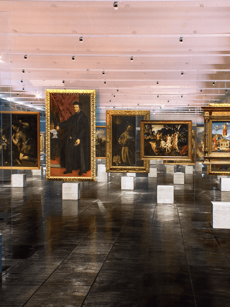 Elegant art gallery showcasing historical paintings with ornate frames and modern lighting.