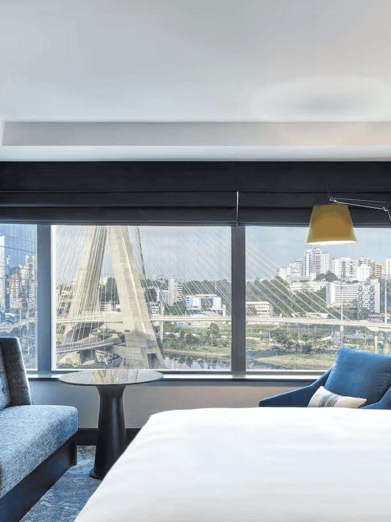 Modern city skyline view from hotel window with bridge and urban landscape.