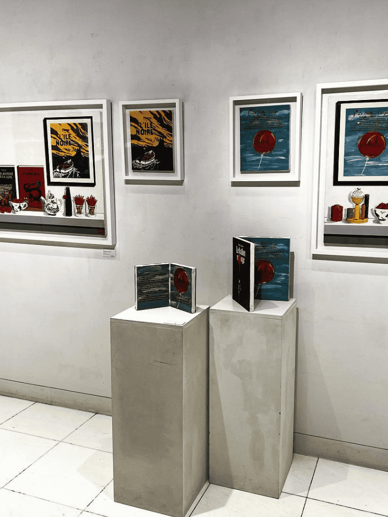Art gallery display of modern posters and books, minimalistic white frames, clean gallery setting.