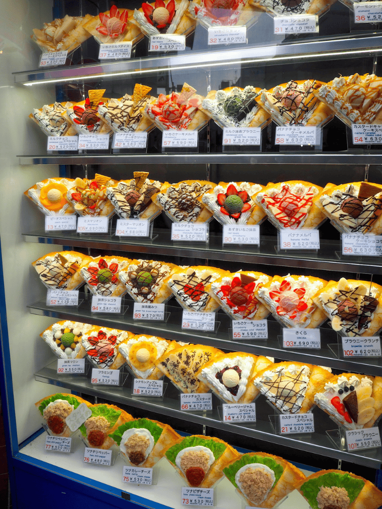 Assorted colorful desserts display with strawberries, chocolates, and toppings at a bakery showcase.