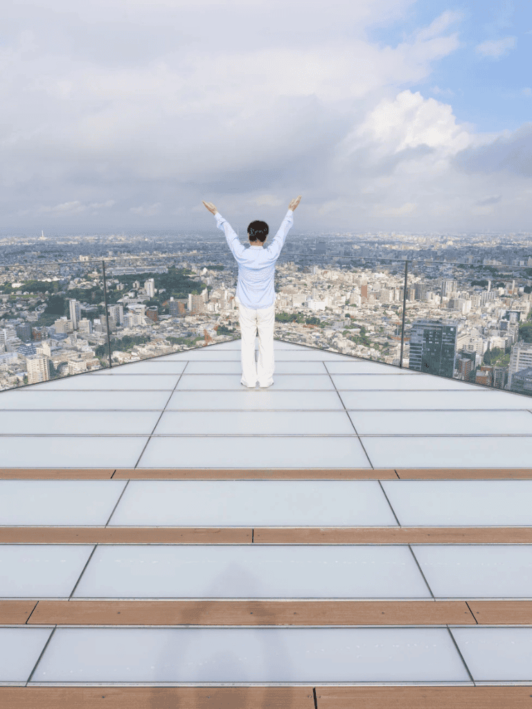 Overlooking city skyline from rooftop with arms raised, inspiring adventure and navigation.