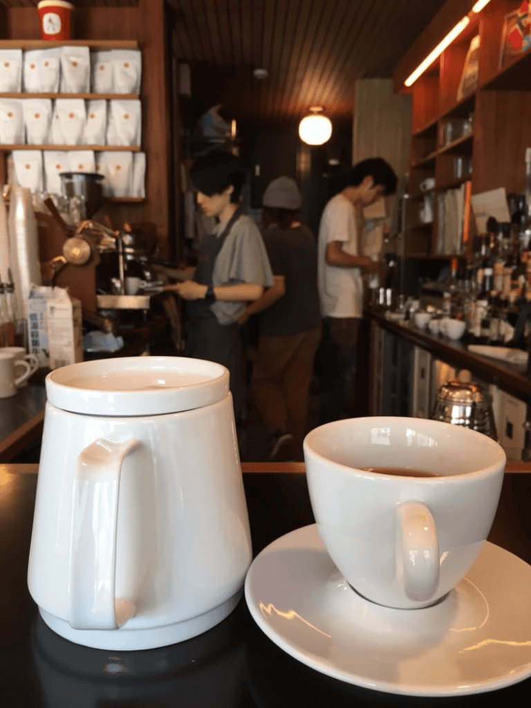 Coffee mug and teapot on a table at a cozy café.