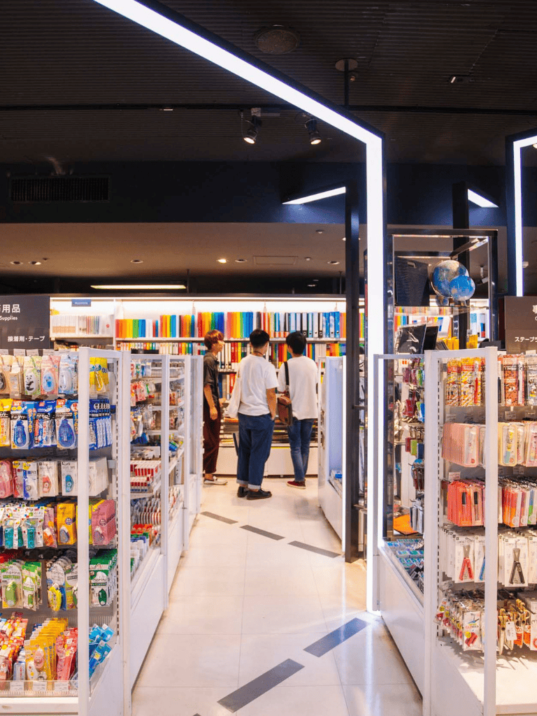 Colorful bookstore aisle with students exploring and shopping for school supplies, monitors, and educational materials.